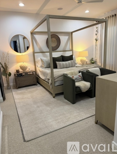 A bedroom with a four-poster bed and a round mirror on the wall.