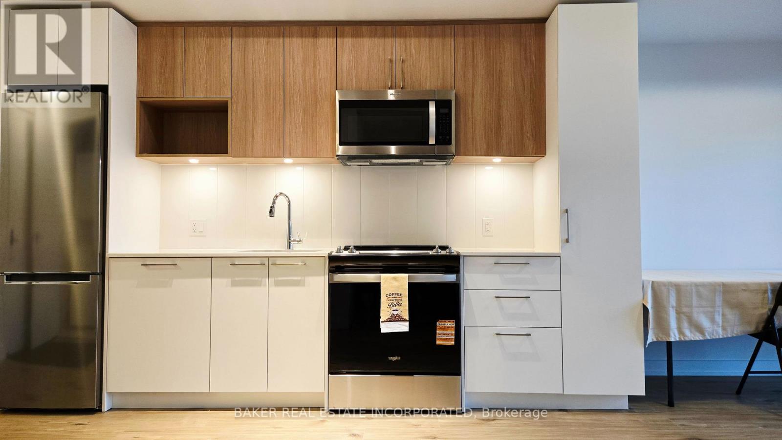 A kitchen with a refrigerator, microwave, oven, and cabinets.