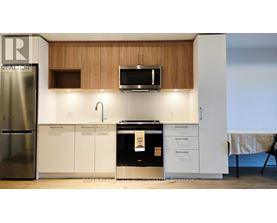 A kitchen with a refrigerator, microwave, oven, and cabinets.