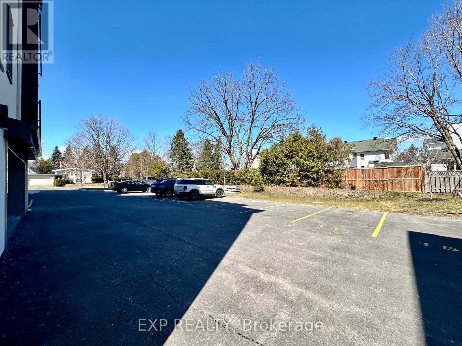 A parking lot with a few cars and trees in the background.
