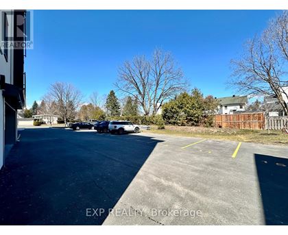 A parking lot with a few cars and trees in the background.