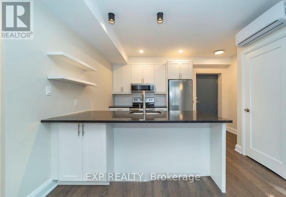 A kitchen with white cabinets and a black countertop.