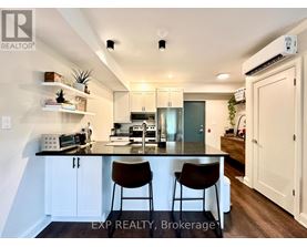 A kitchen with white cabinets and a black countertop with two chairs.