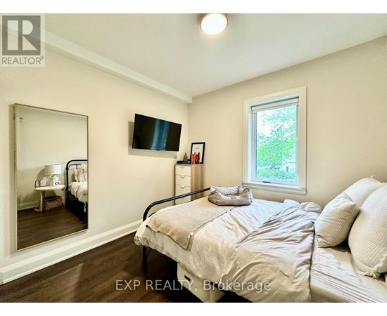 A bedroom with a bed, dresser, mirror, and window.