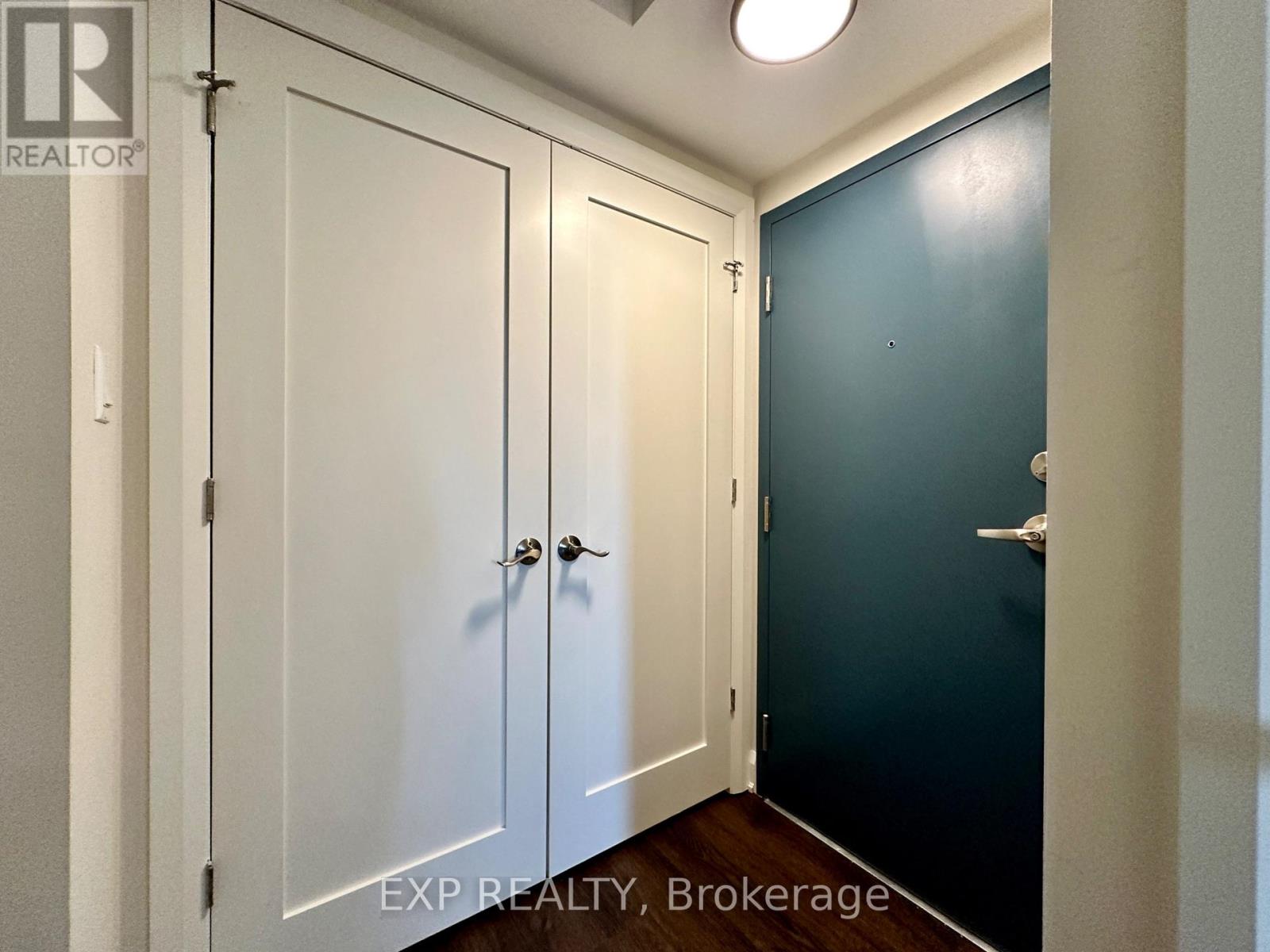 A hallway with two doors and a brokerage sign.