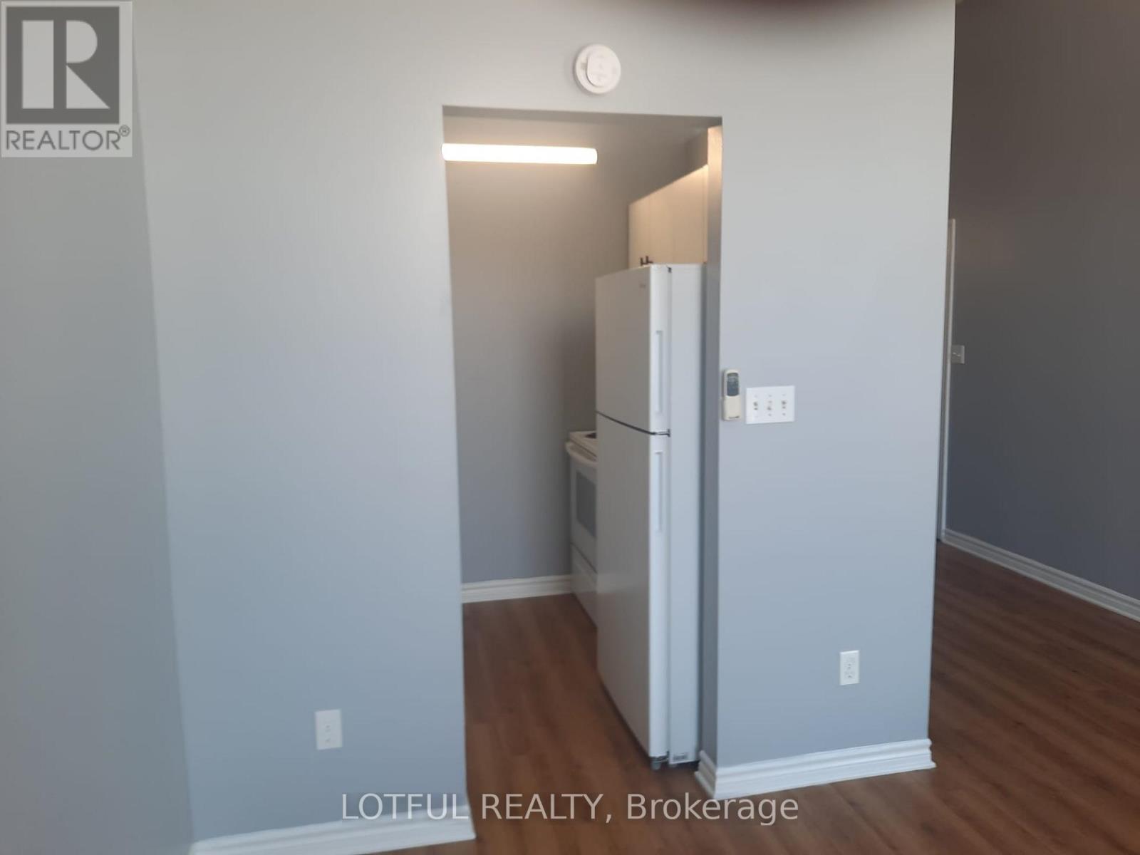 A white refrigerator in a room with light wood flooring.