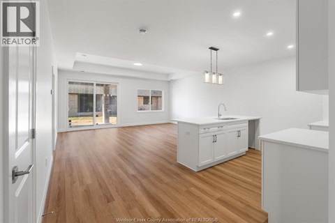 A kitchen with white cabinets and a wooden floor.