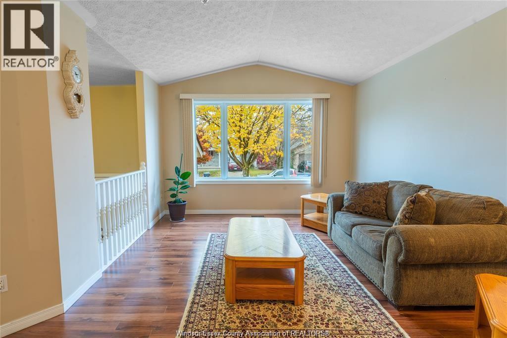 A living room with a couch, coffee table, and a window with autumn leaves.