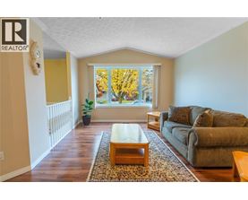 A living room with a couch, coffee table, and a window with autumn leaves.