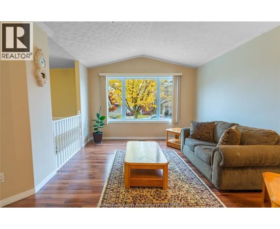 A living room with a couch, coffee table, and a window with autumn leaves.
