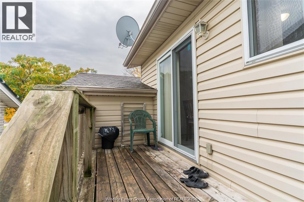 A wooden deck with a pair of shoes and a green chair is in front of a house.