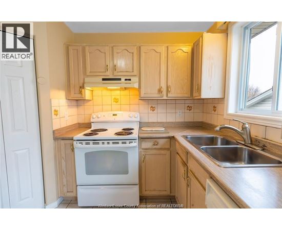 A kitchen with a white stove and wooden cabinets.