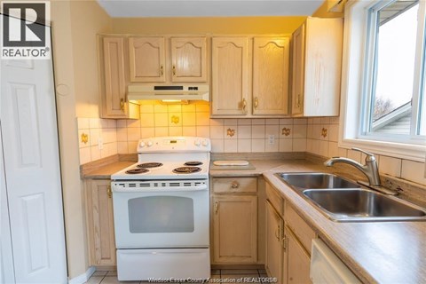 A kitchen with a white stove and wooden cabinets.