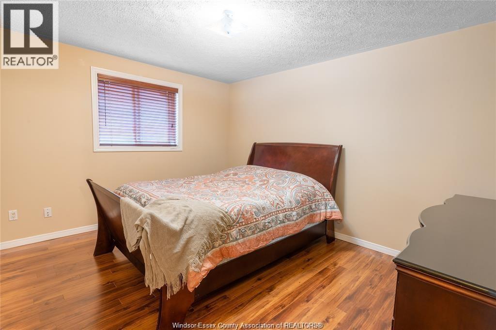 A bedroom with a bed, wooden floors, and a window with blinds.