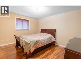 A bedroom with a bed, wooden floors, and a window with blinds.