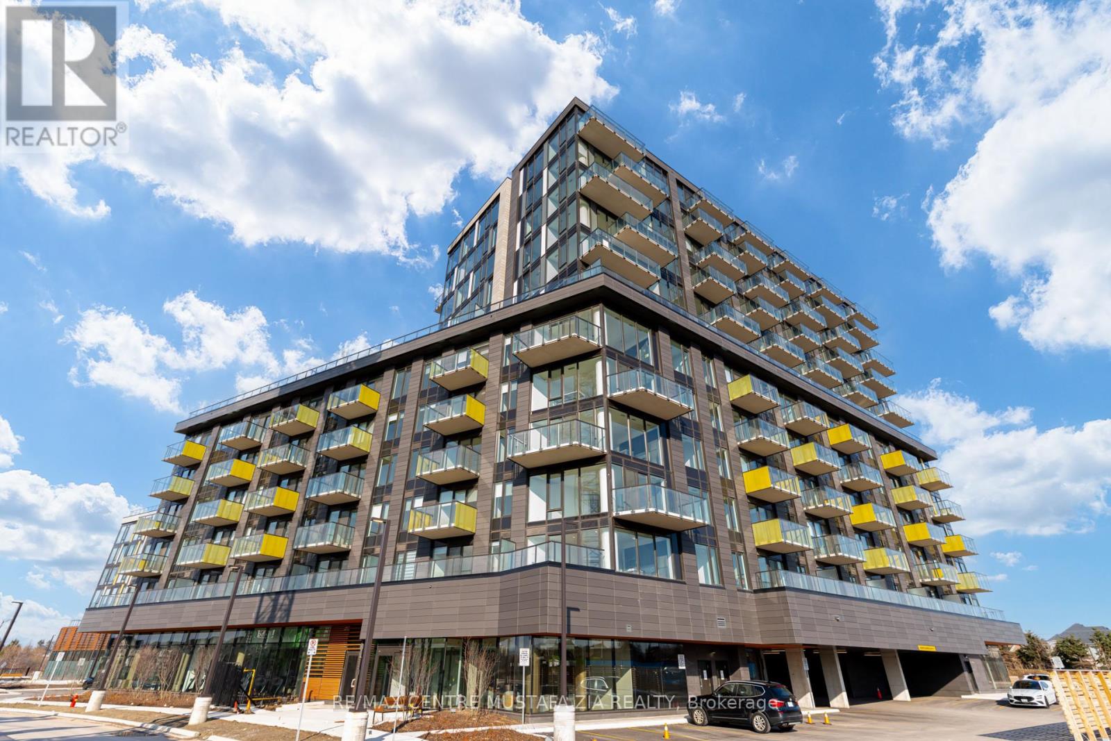 A modern multi-story building with a glass facade and yellow balconies.