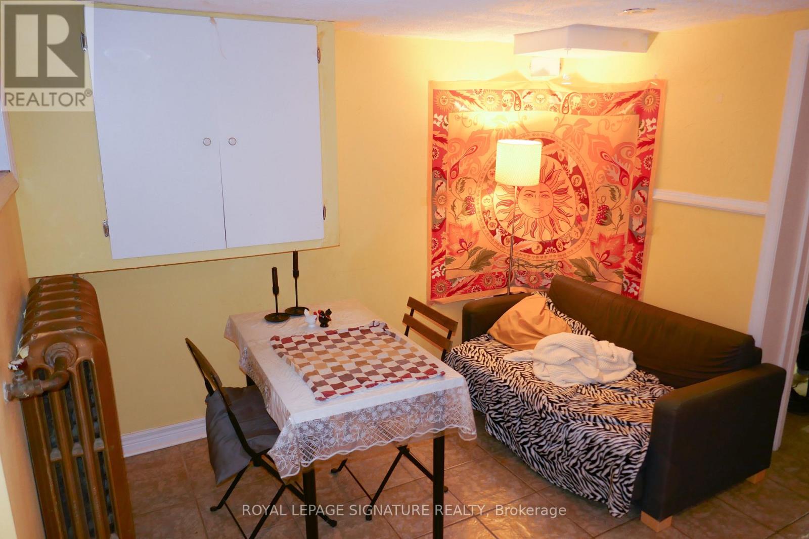 A room with a bed, a chair, a table, and a cabinet.