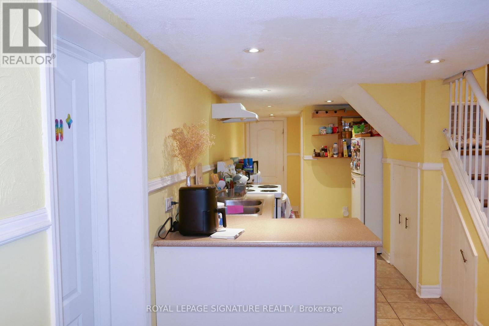A kitchen with yellow walls and white cabinets.