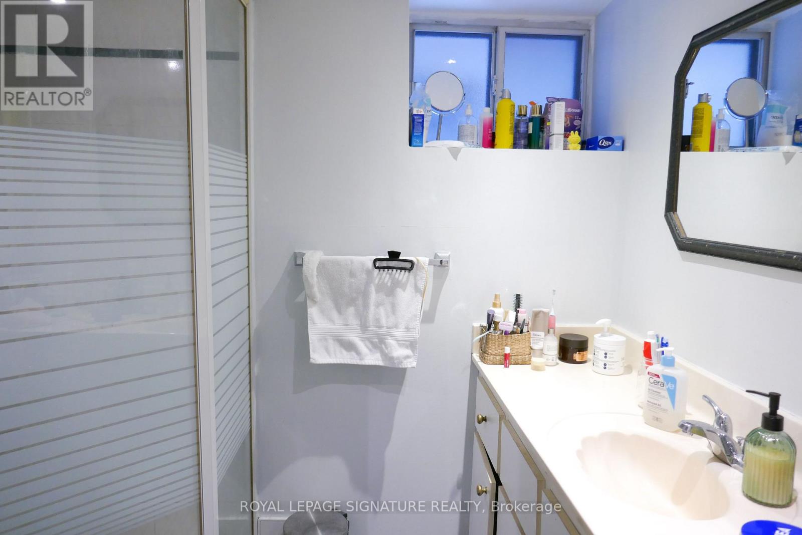 A white bathroom with a white sink and a white towel hanging on the wall.