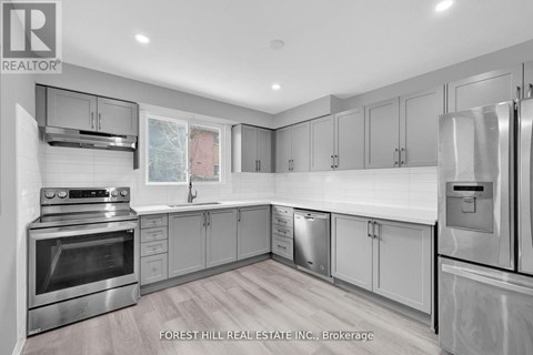 A modern kitchen with stainless steel appliances and wooden flooring.