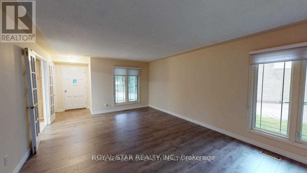 A spacious room with wooden floors and a large window.