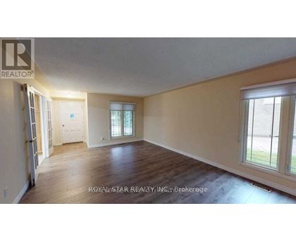 A spacious room with wooden floors and a large window.