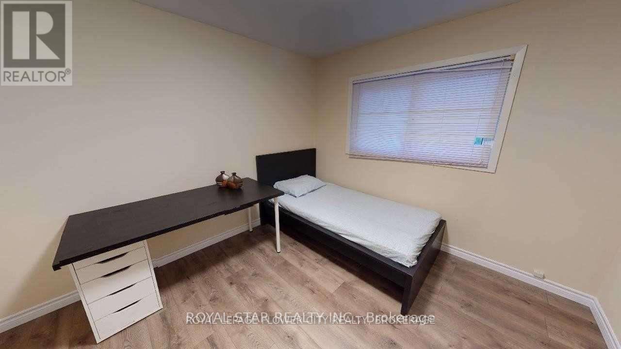 A bedroom with a bed, desk, and drawers.