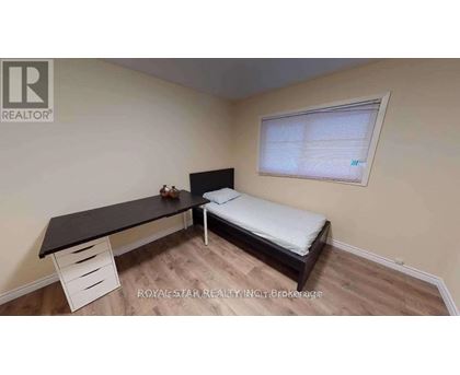 A bedroom with a bed, desk, and drawers.