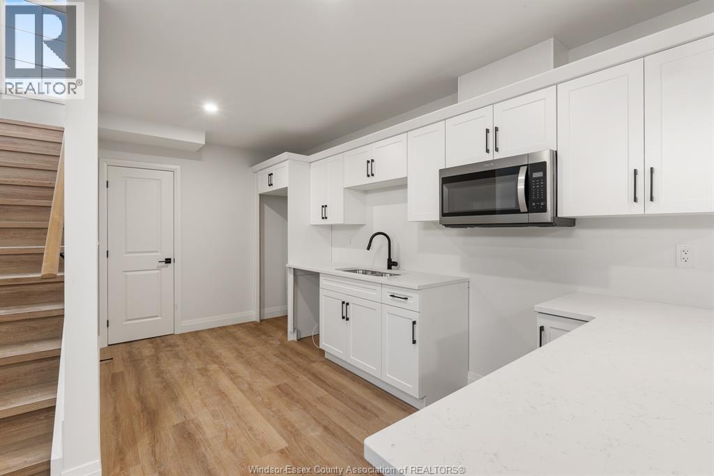 A kitchen with white cabinets and a wooden floor.
