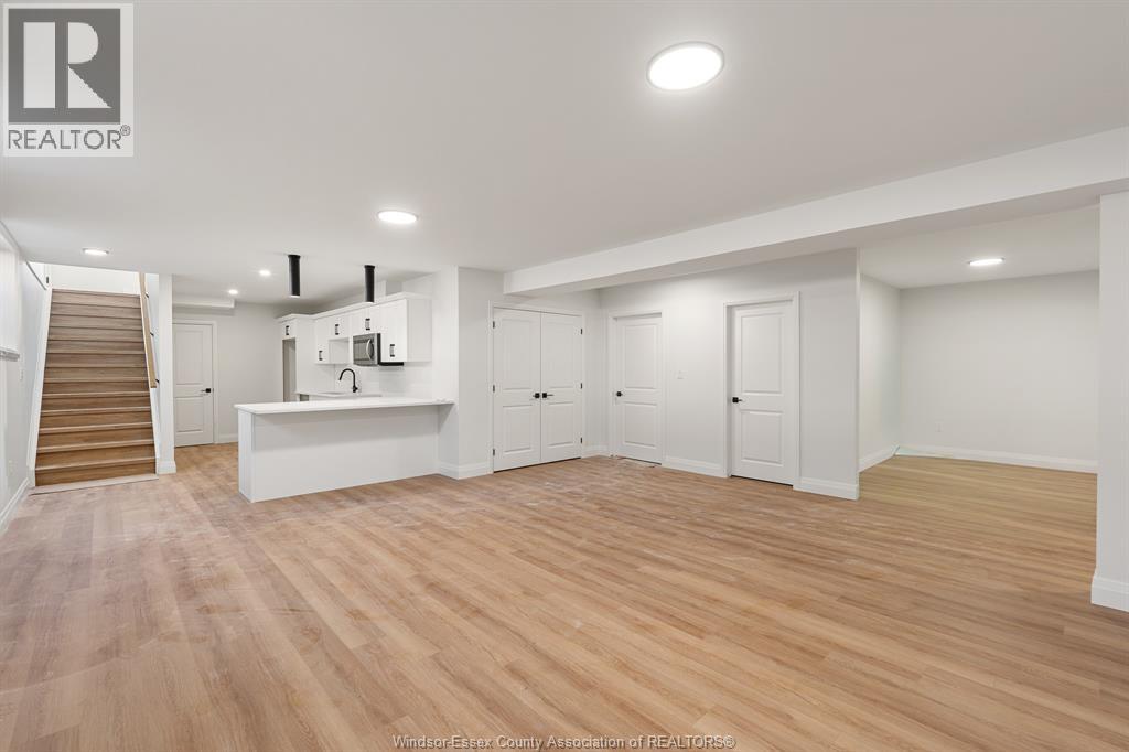 A spacious room with wooden flooring and white walls.