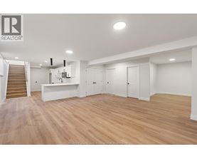 A spacious room with wooden flooring and white walls.