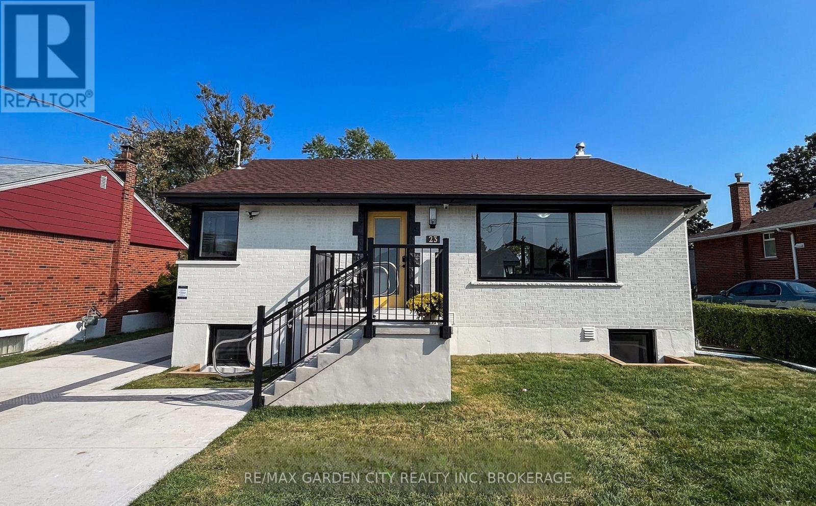 A house with a white brick exterior and a black metal railing on the front porch.