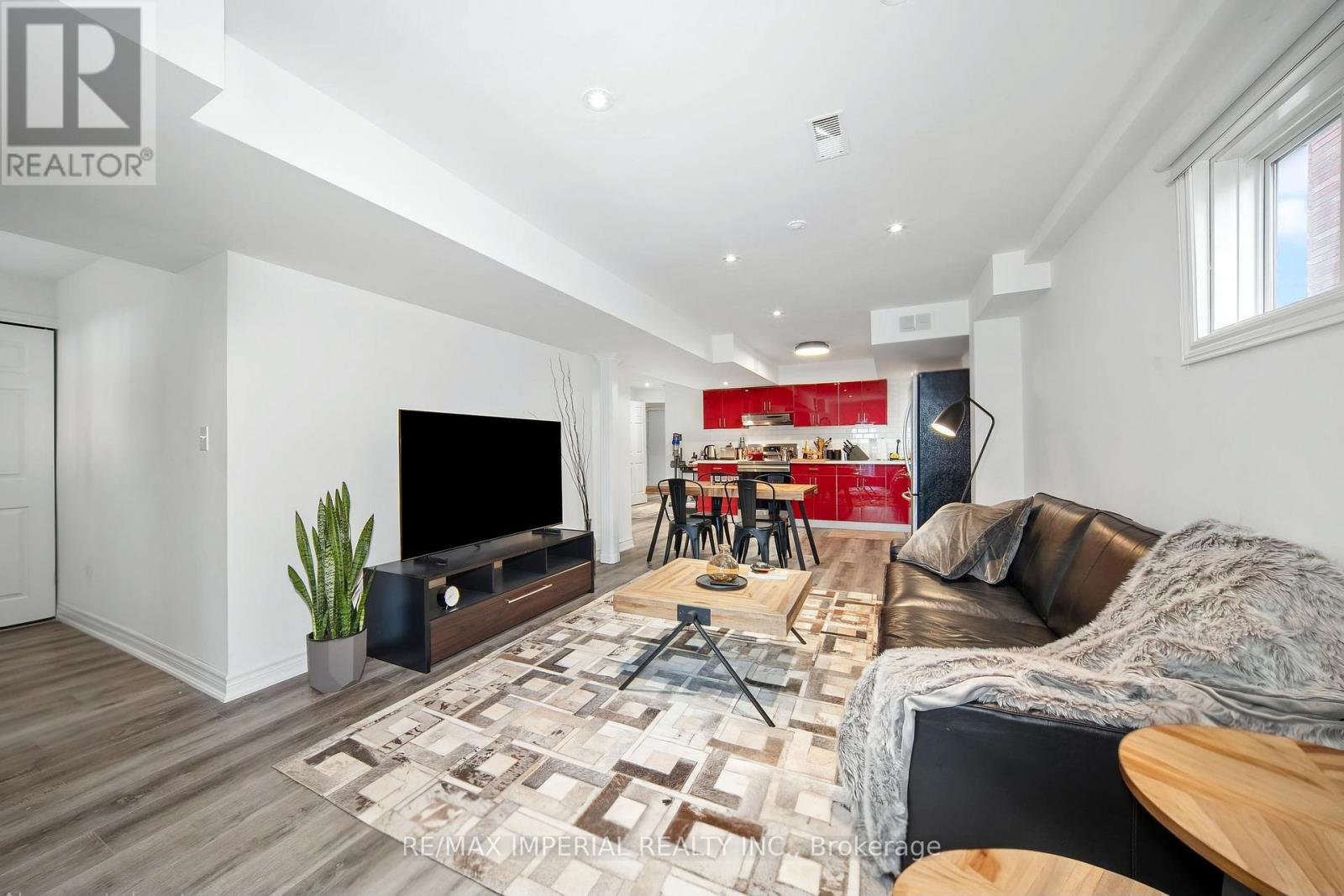 A living room with a brown leather couch and a wooden floor.
