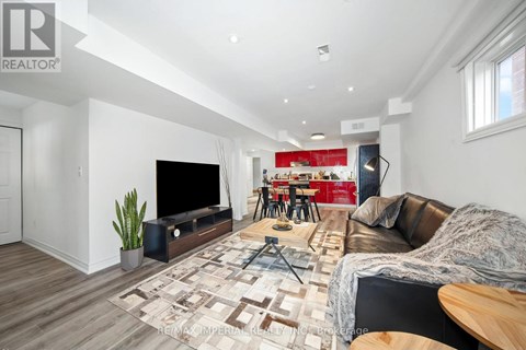 A living room with a brown leather couch and a wooden floor.