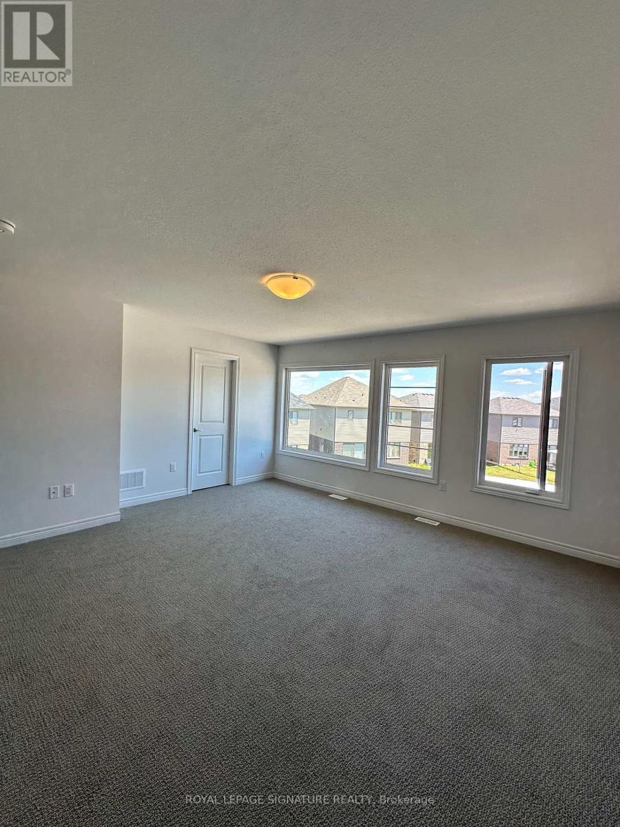 A room with a carpet floor and a window showing a building.