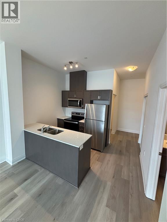 A modern kitchen with a stainless steel refrigerator and microwave.