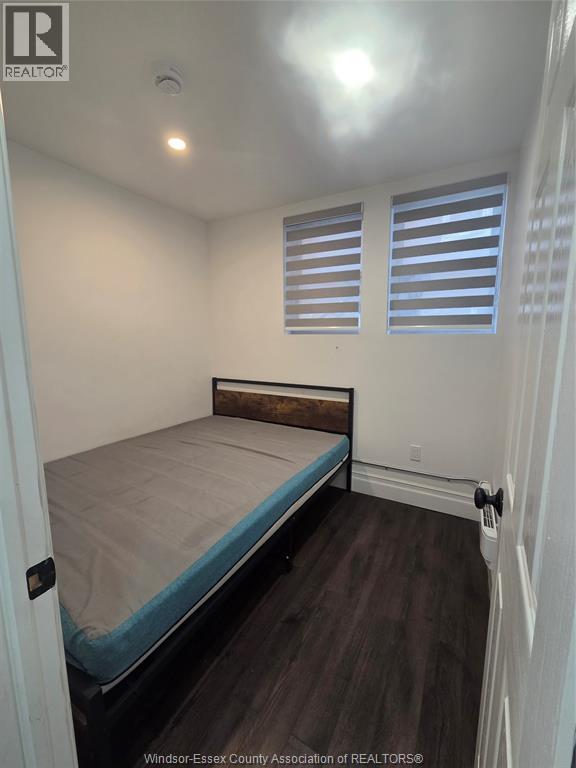 A bedroom with a bed, wooden floor, and white walls.