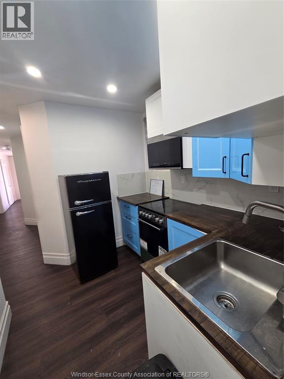A kitchen with a black fridge and stove top oven.