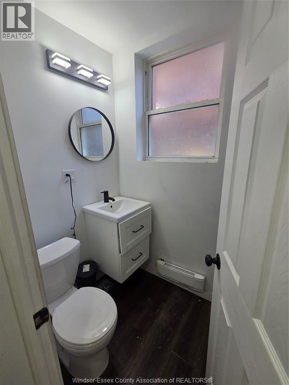 A white toilet with a white cabinet and a round mirror above it.