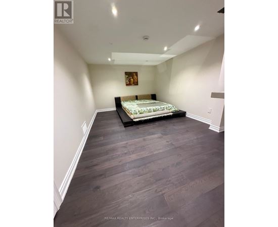 A bedroom with a bed in the middle and a painting on the wall.