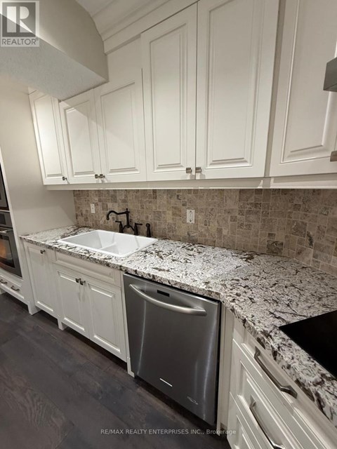 A kitchen with white cabinets and a granite countertop.