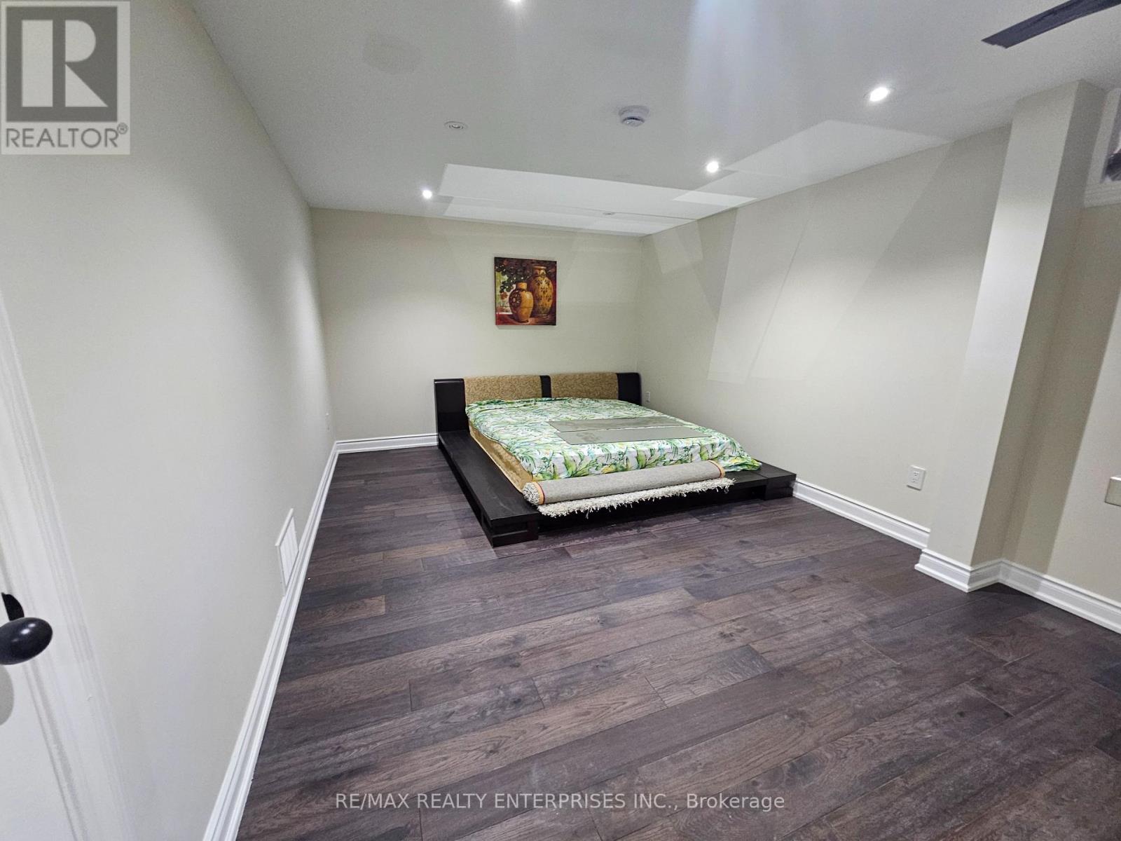 A room with wooden flooring and a window letting in sunlight.