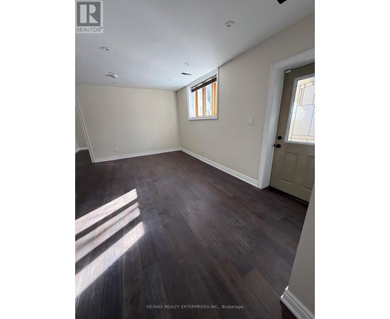 A room with wooden flooring and a window letting in sunlight.
