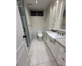 A white bathroom with a toilet, sink, and shower.