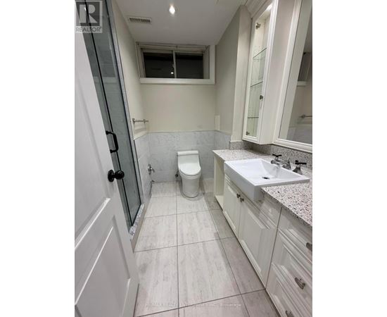 A white bathroom with a toilet, sink, and shower.
