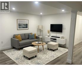 A living room with a grey couch, a coffee table, a lamp, a TV, and a framed picture on the wall.