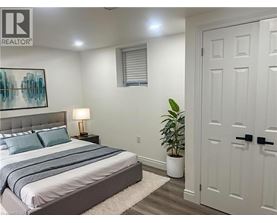 A bedroom with a bed, a lamp, and a plant.
