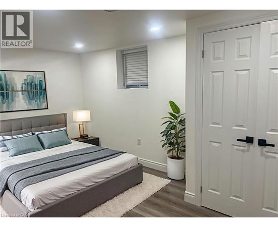 A bedroom with a bed, a lamp, and a plant.