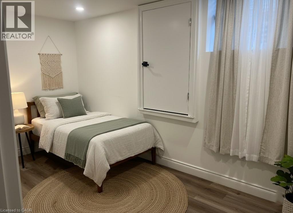A bedroom with a bed, a nightstand, and a window with curtains.