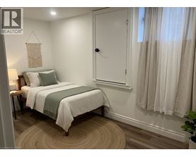 A bedroom with a bed, a nightstand, and a window with curtains.